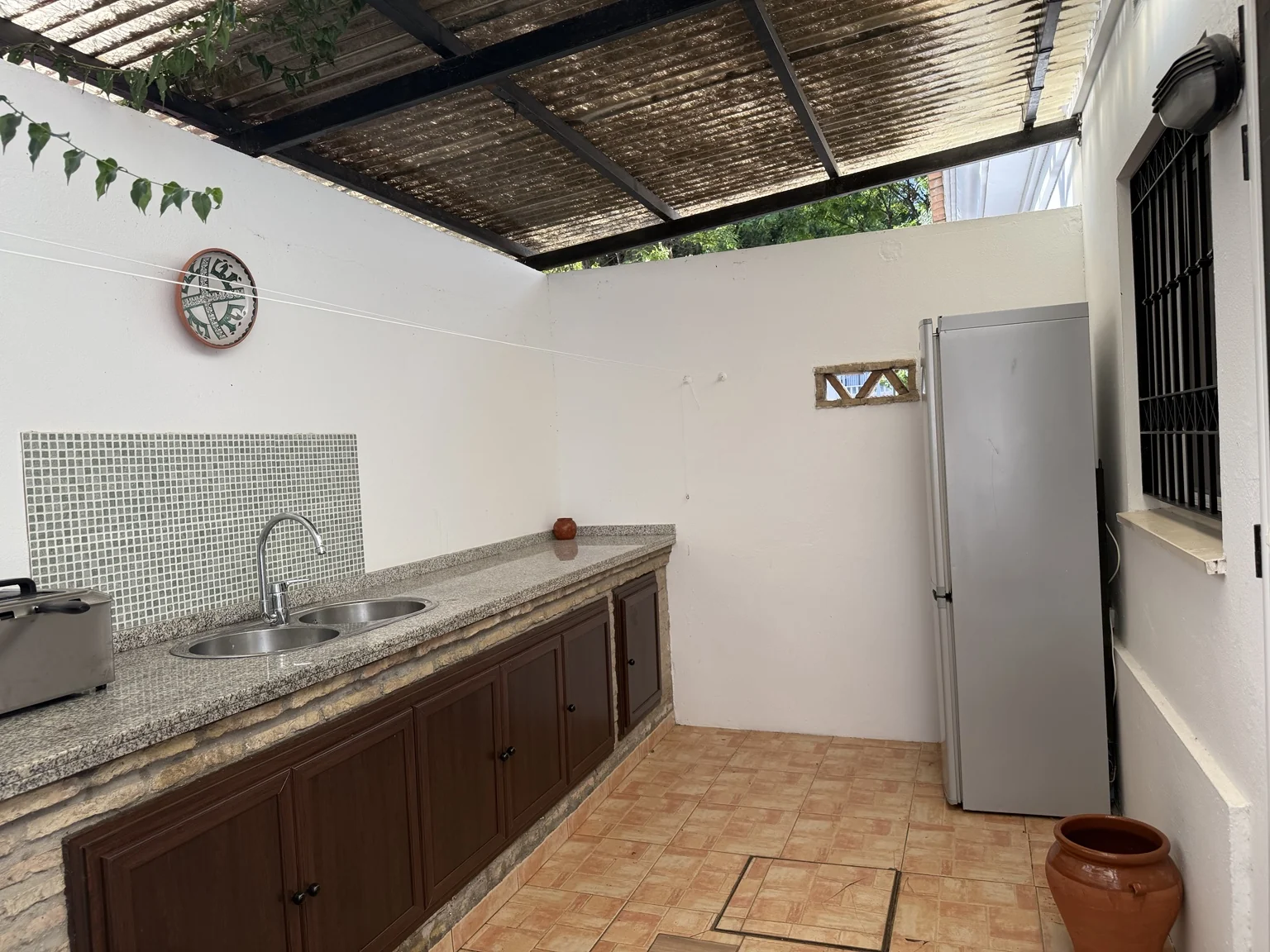 Covered utility kitchen with double sink and extra refrigerator